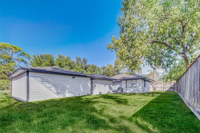 a view of a backyard with large trees and wooden fence