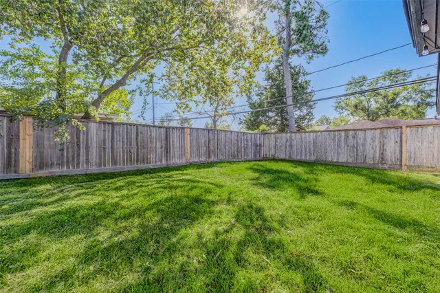 a view of a backyard with large trees and wooden fence