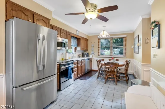 a kitchen with stainless steel appliances a refrigerator a stove a sink a dining table and chairs with wooden floor