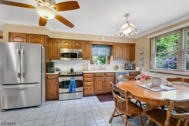 a kitchen with a refrigerator a stove a sink dishwasher a dining table and chairs with wooden floor