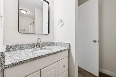 a bathroom with a granite countertop sink and a mirror