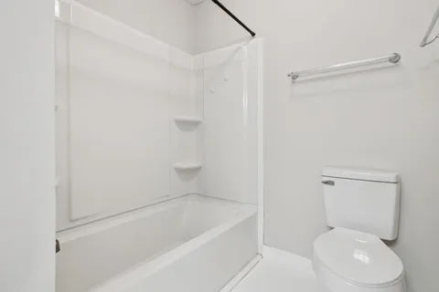 a white toilet sitting next to a bath tub