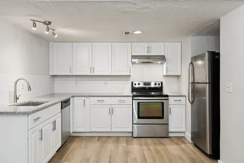 a kitchen with stainless steel appliances granite countertop a stove a refrigerator and a sink