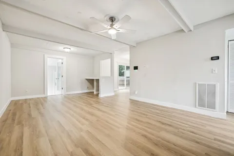 a view of an empty room with wooden floor and a ceiling fan