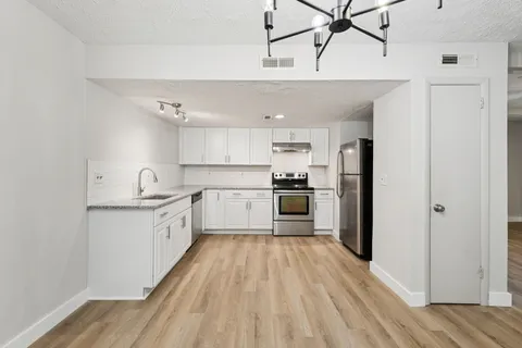 a kitchen with cabinets wooden floor and stainless steel appliances