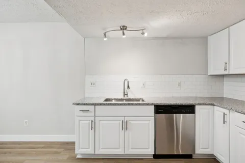 a kitchen with granite countertop white cabinets and a sink