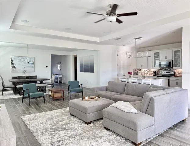 a kitchen with stainless steel appliances granite countertop a stove a sink dishwasher a refrigerator a stove and white cabinets with wooden floor