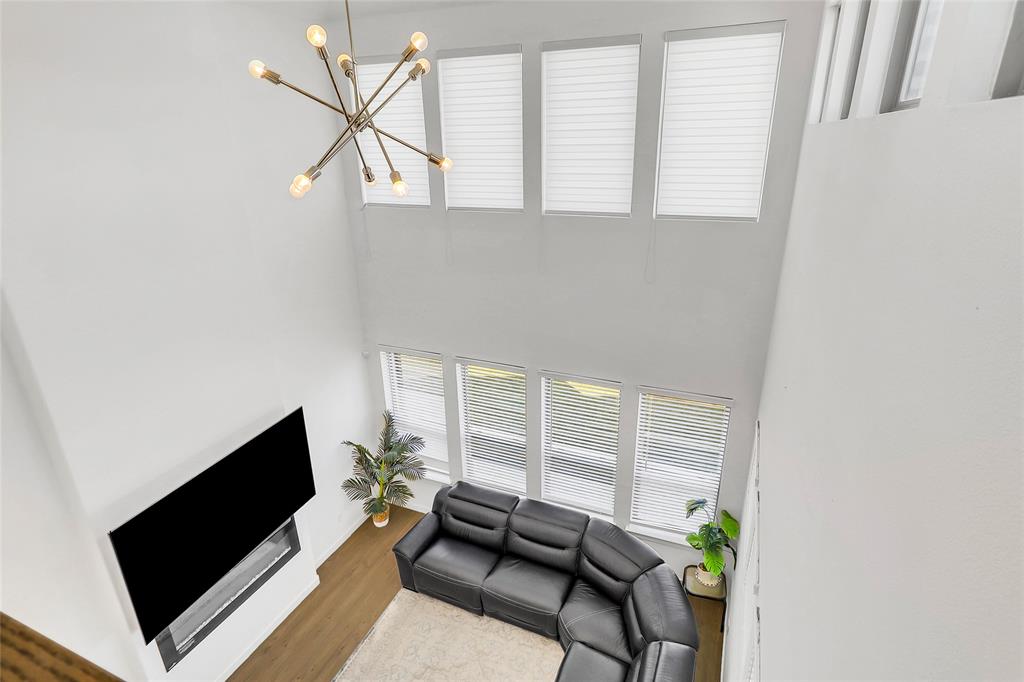 1241 Lupine Road Prosper, TX 75078 - Photo 25 of 38 Two-story living area featuring a modern linear chandelier, wood-finish flooring, and multiple large windows