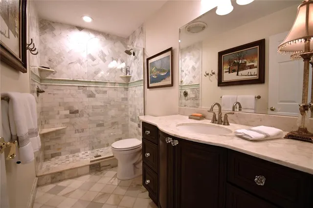 a bathroom with a granite countertop sink a toilet a mirror and shower