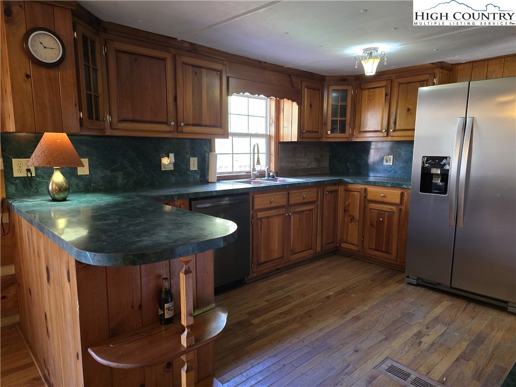 3160 Roundabout Road Creston, NC 28615 - Photo 18 of 50 a kitchen with stainless steel appliances granite countertop a sink dishwasher a stove a refrigerator and a microwave oven with wooden floor