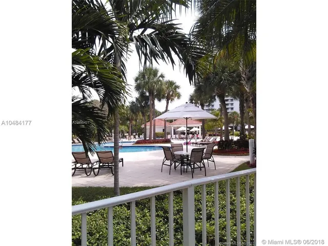 a view of a patio with table and chairs under an umbrella with potted plants