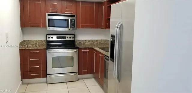 a kitchen with granite countertop a stove and a microwave with cabinets