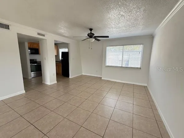 an empty room with chandelier fan and windows