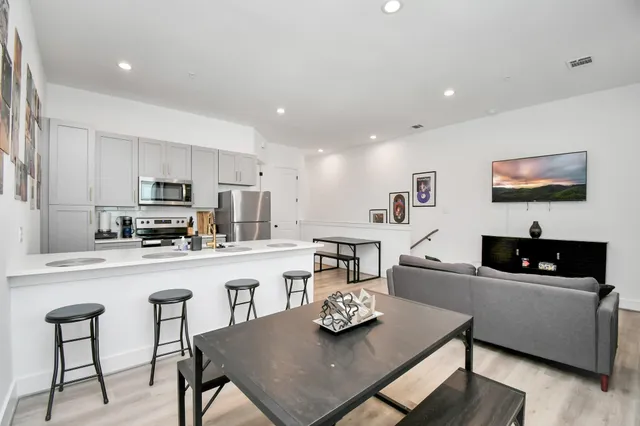 a kitchen with stainless steel appliances granite countertop a stove a refrigerator a sink a dining table and chairs with wooden floor