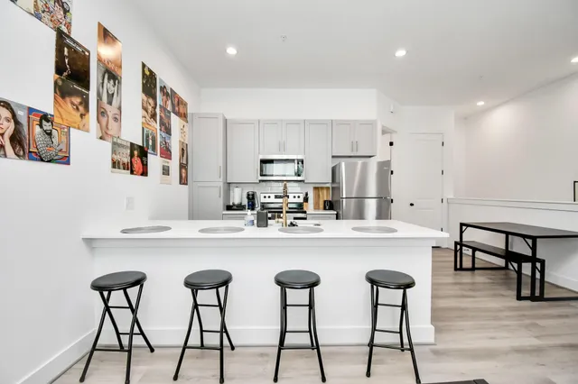 a kitchen with stainless steel appliances a table chairs and a refrigerator