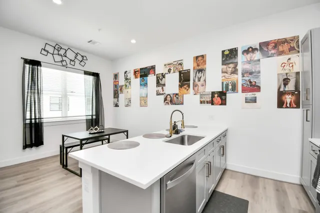 a kitchen that has a lot of cabinets a sink and wooden floor