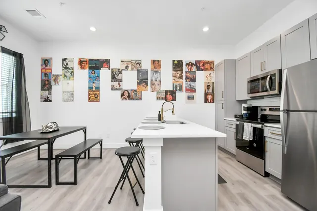 a kitchen with stainless steel appliances kitchen island granite countertop a refrigerator and a stove top oven with wooden floor