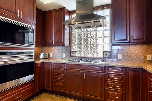 a kitchen with stainless steel appliances granite countertop wooden cabinets and a stove top oven