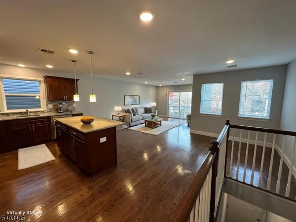 a large living room with stainless steel appliances granite countertop a couch wooden floor and a view of kitchen