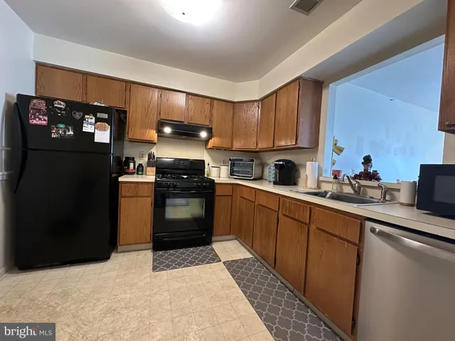 a kitchen with stainless steel appliances granite countertop a refrigerator a sink dishwasher a stove top oven a refrigerator and cabinets