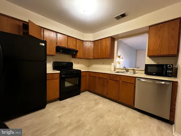 a kitchen with granite countertop a refrigerator stove top oven a sink and dishwasher