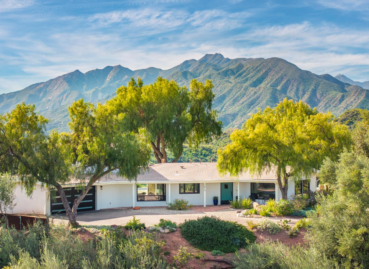1417 Foothill Road Ojai, CA 93023 - Photo 7 of 41 a view of a white house with a swimming pool and lawn chairs under an umbrella
