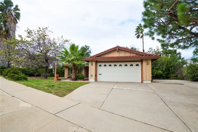 a front view of a house with a garden and trees