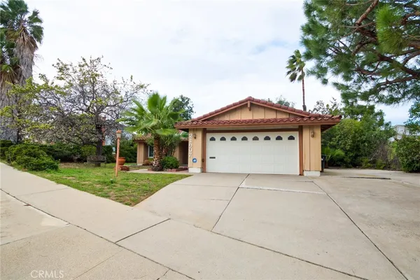 a front view of a house with a garden and trees