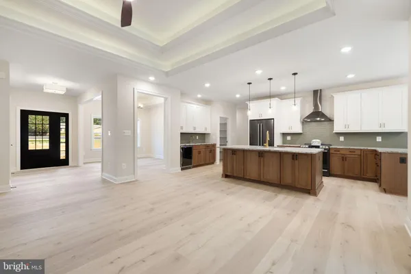 a large kitchen with stainless steel appliances a large center island wooden floor and cabinets