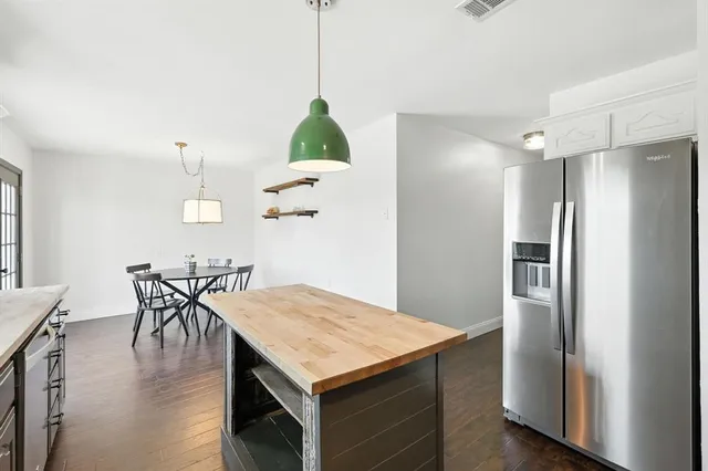 a kitchen with stainless steel appliances granite countertop a table chairs and refrigerator