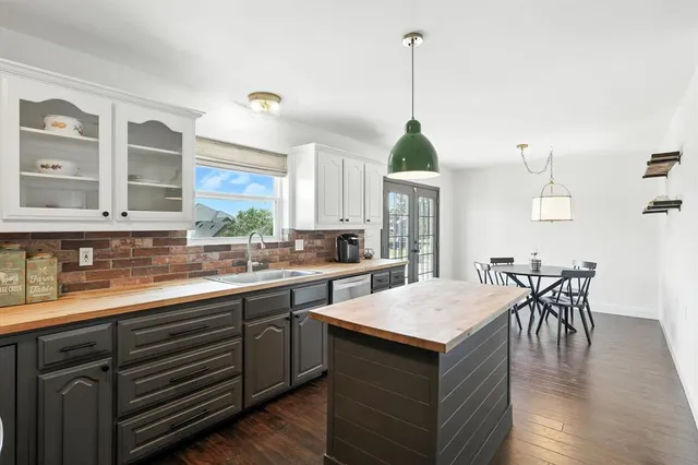 a kitchen with a stove a kitchen island a sink dishwasher a dining table and chairs with wooden floor