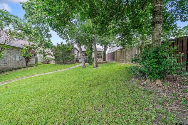 a view of a house with a big yard and large trees