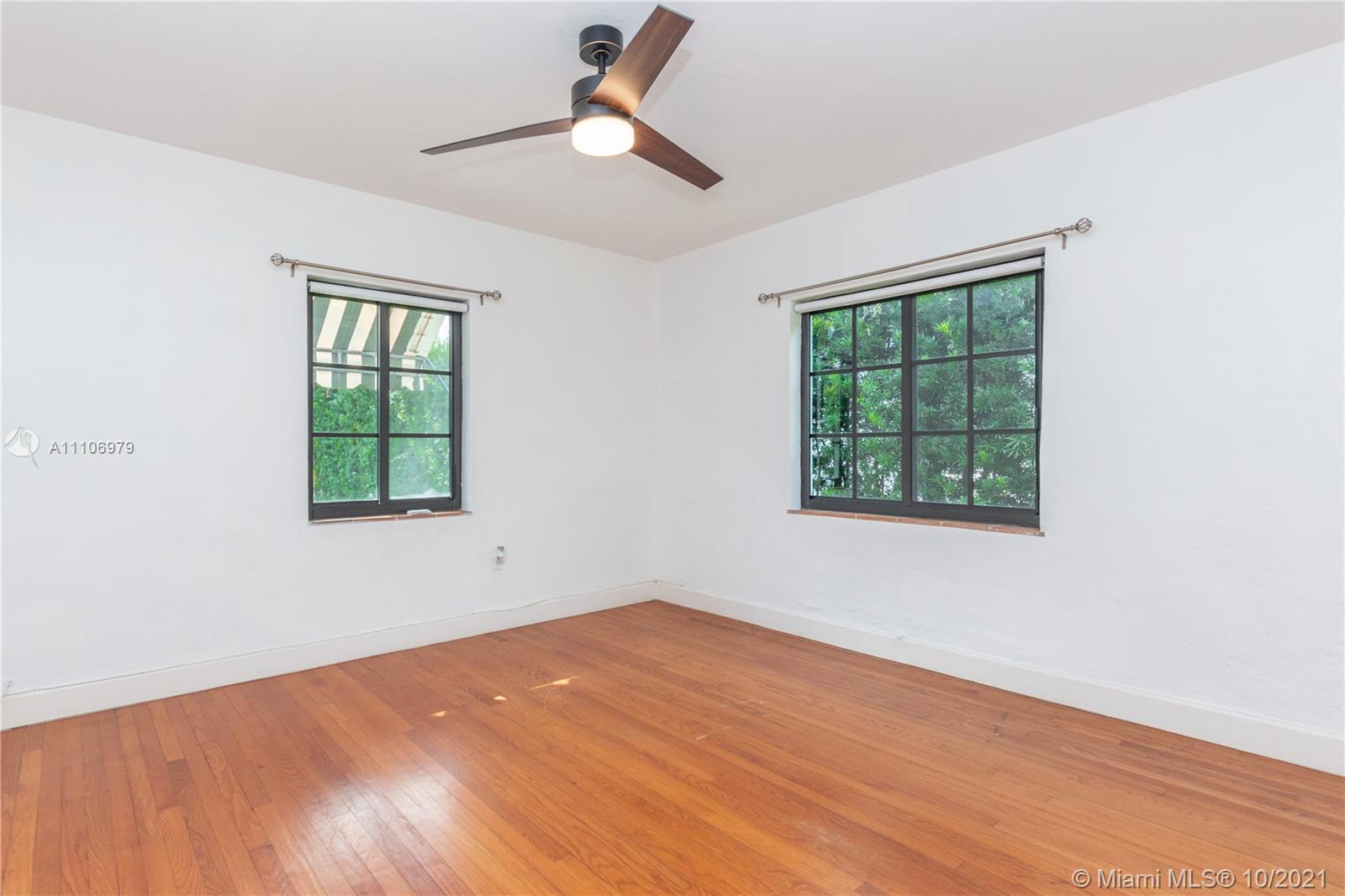 5173 Alton Road Miami Beach, FL 33140 - Photo 11 of 31 an empty room with wooden floor ceiling fan and windows