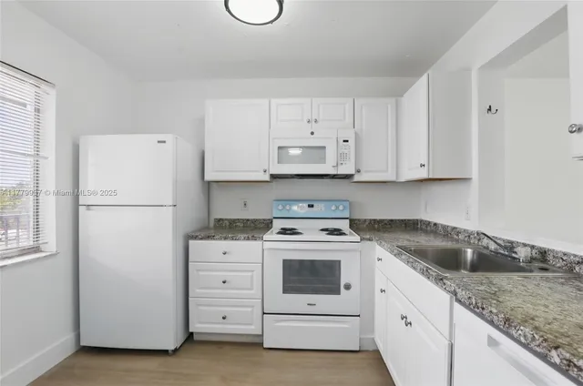 a kitchen with granite countertop white cabinets and white appliances