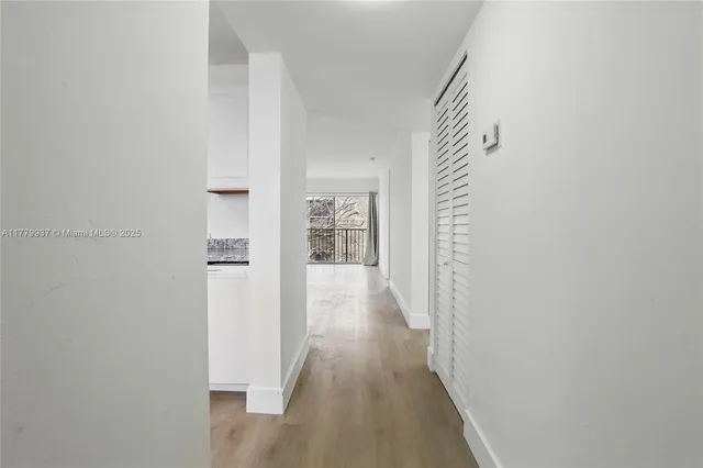a view of a hallway with wooden floor and closet