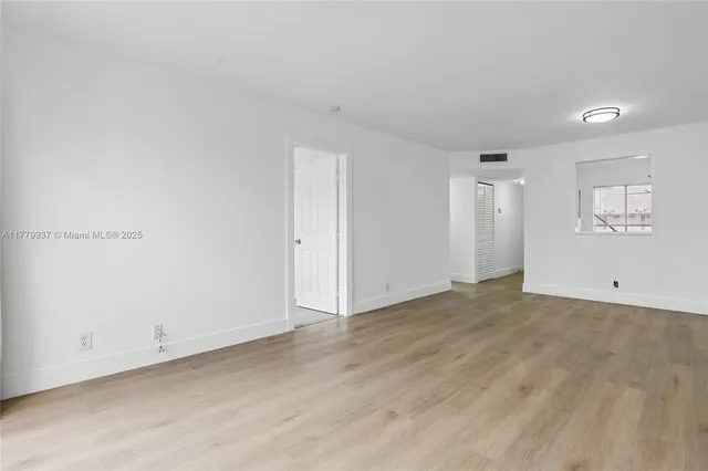 a view of empty room with wooden floor and windows
