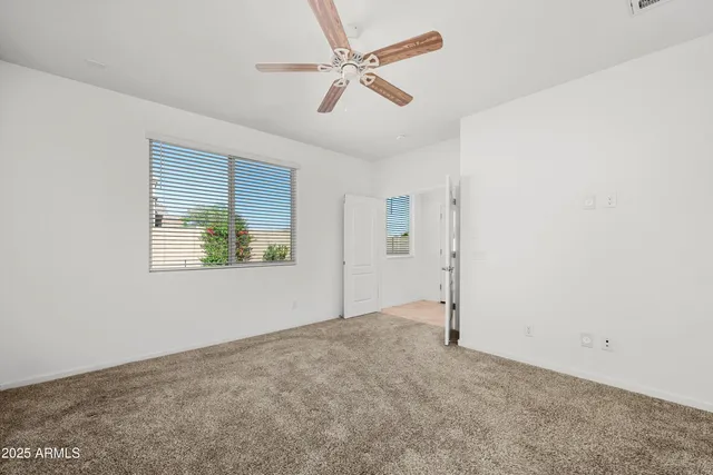 an empty room with windows and fan