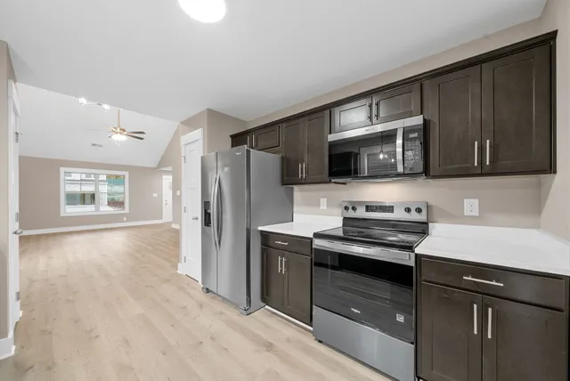 a kitchen with stainless steel appliances a stove a sink a microwave a refrigerator and cabinets