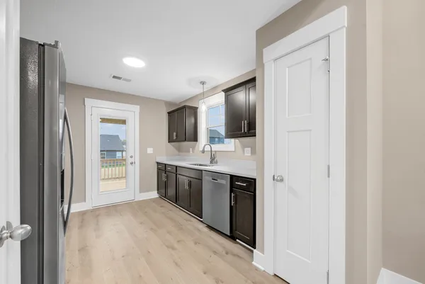 a view of a kitchen with a sink and dishwasher a refrigerator with wooden floor