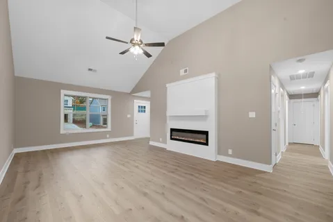 a view of an empty room with window and wooden floor