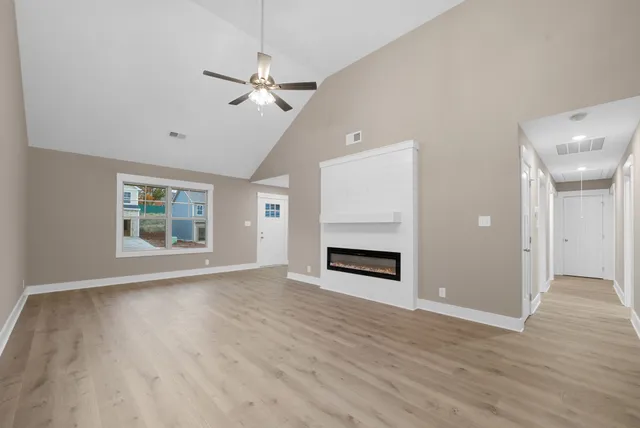 a view of an empty room with window and wooden floor