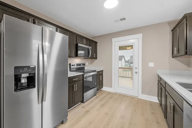 a kitchen with stainless steel appliances granite countertop a refrigerator and a stove top oven