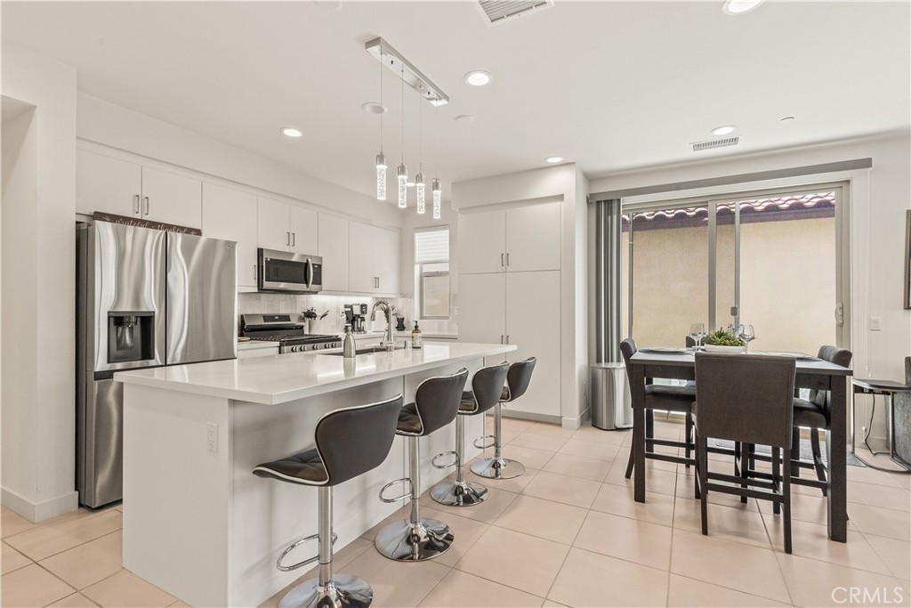 80281 Redstone Way La Quinta, CA 92253 - Photo 6 of 21 a kitchen with stainless steel appliances a dining table chairs refrigerator and sink