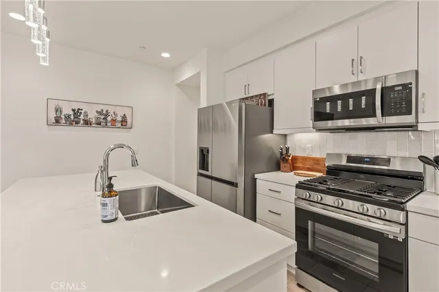 a kitchen with stainless steel appliances a refrigerator a sink a stove and cabinets