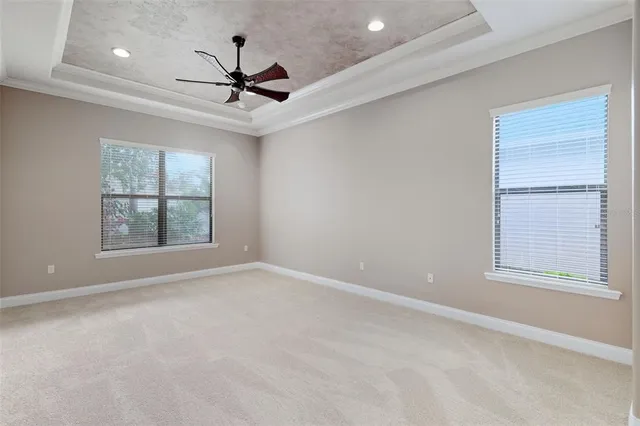 an empty room with windows and ceiling fan