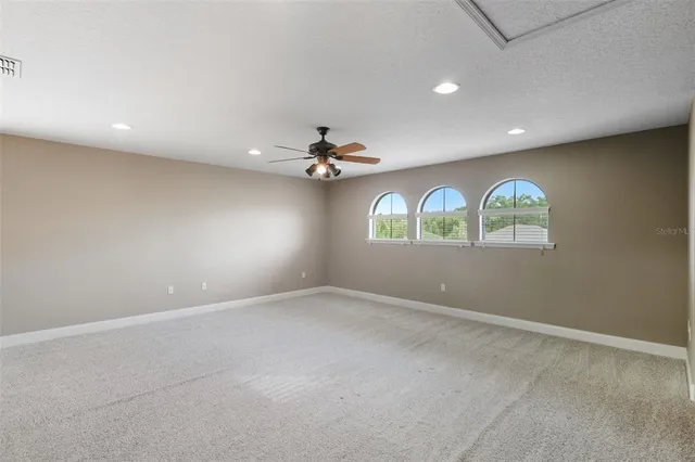an empty room with windows and chandelier fan