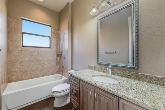 a bathroom with a granite countertop sink a toilet and bathtub