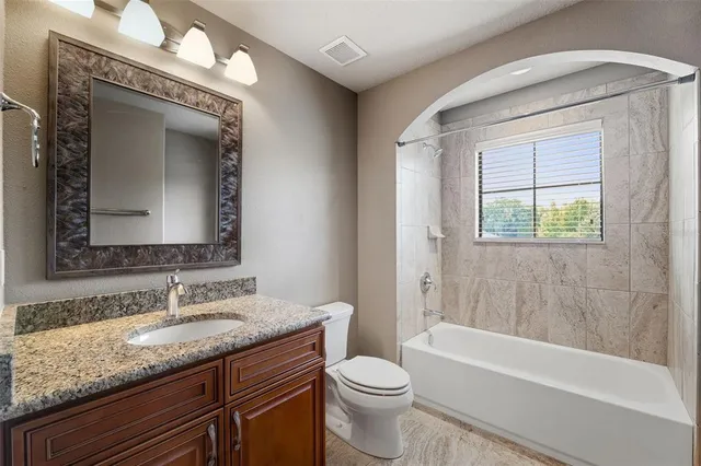 a bathroom with a granite countertop toilet a sink and bathtub
