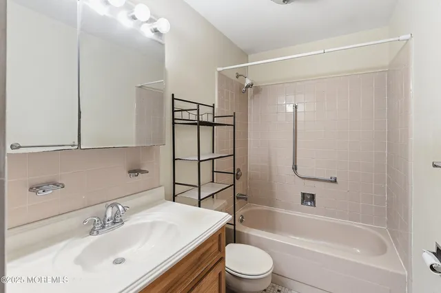 a bathroom with a bathtub shower sink vanity and toilet