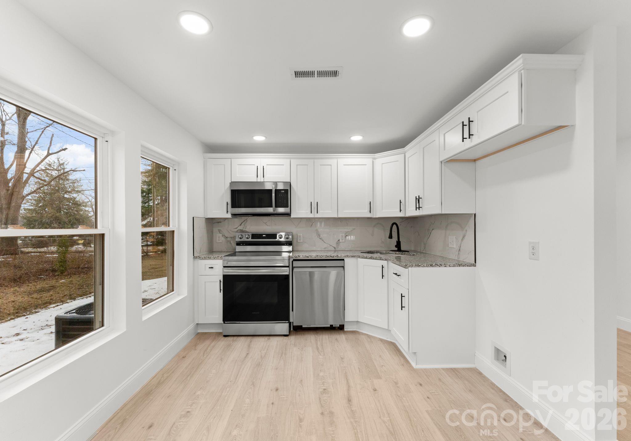 1413 Modena Street Gastonia, NC 28054 - Photo 20 of 27 a kitchen with stainless steel appliances granite countertop a stove top oven a sink and a refrigerator